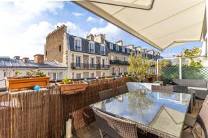 - un balcon avec une table, des chaises et des bâtiments dans l'établissement Chambre d'Amis, à Paris