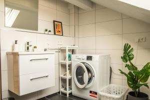 eine weiße Waschküche mit Waschmaschine und Trockner in der Unterkunft Das RAUM-Wunder mit Küche und Smart-TV in Karlsruhe