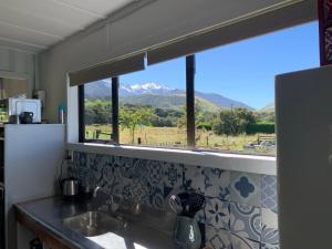 a kitchen with a sink and a window with mountains at Alpine Manuka View Cabin in Kaikoura