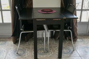 een zwarte tafel met twee stoelen en een bord erop bij Petite maison indépendante in Nîmes
