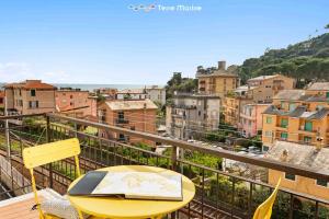 a yellow table and chairs on a balcony with a city at La Tana del Polpo in Monterosso al Mare