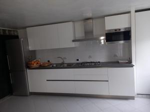 a kitchen with white cabinets and a sink and a refrigerator at HOME SWEET HOME in Rovereto