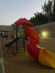 un parque infantil con un tobogán rojo y amarillo en un arenero en Studio alto padrão confortável sem taxa de limpeza, en Cachoeira do Sul