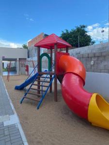 un parque infantil con un tobogán rojo y amarillo y una estructura de juegos en Studio alto padrão confortável sem taxa de limpeza, en Cachoeira do Sul