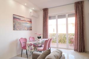 a dining room with a table and pink chairs at Napoli Central Lumina Suites in Naples