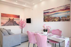 a dining room with a table and pink chairs at Napoli Central Lumina Suites in Naples