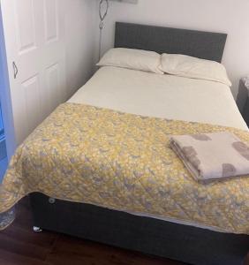 ein Bett mit einem schwarzen Rahmen und einer gelben Decke in der Unterkunft Solihull Guest House 1 in Olton