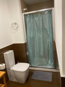 łazienka z toaletą i niebieską zasłoną prysznicową w obiekcie Estudio Céntrico D1 w mieście Oviedo