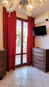 ein Wohnzimmer mit roten Vorhängen und einem TV in der Unterkunft B&B Madonna della Neve in Stresa