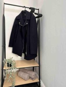 un cappotto nero appeso a un appendiabiti con asciugamani di Spacious One-Bedroom in St. Helens a Burtonwood