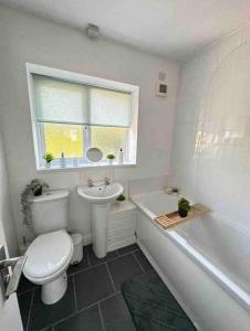 a bathroom with a toilet and a sink and a window at Spacious One-Bedroom in St. Helens in Burtonwood