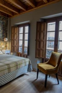1 dormitorio con 1 cama, 1 silla y ventanas en Las Musas, Casa Rural en Hervás
