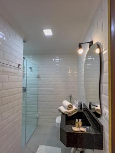 ein Bad mit einem Waschbecken und einer Glasdusche in der Unterkunft Pousada Do Conde in Campos do Jordão