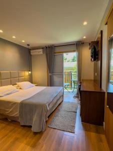 ein Schlafzimmer mit einem großen Bett und einem Balkon in der Unterkunft Pousada Do Conde in Campos do Jordão