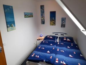 a bedroom with a bed with blue sheets and pictures on the wall at Whg Meeresblick in Nieblum