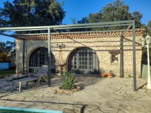 een stenen patio met een bank en een prieel bij Petite maison indépendante in Nîmes