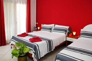 two beds in a room with a red wall at Riviera Ionica in Santa Teresa di Riva