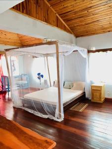 een slaapkamer met een hemelbed in een kamer bij Villa baobab in Ramena