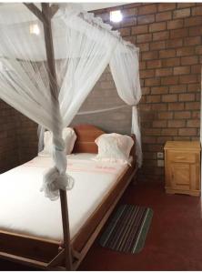 een slaapkamer met een hemelbed en witte gordijnen bij Villa baobab in Ramena