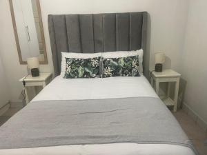 ein Schlafzimmer mit einem großen Bett mit zwei Nachttischen in der Unterkunft Melrose place in Francistown