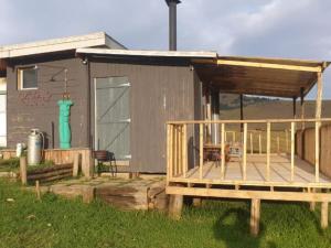 a small building with a deck next to a house at Tin Can Glamping Caravan in Underberg