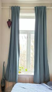 una ventana con cortinas azules en un dormitorio en Oslo-Frogner, en Oslo
