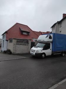 a white truck with a blue trailer parked in front of a house at Mieszkanie 3 pokoje-Faktura in Szczecinek