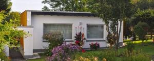 una piccola casa bianca con dei fiori davanti di Haus Hippelstein a Gönnersdorf