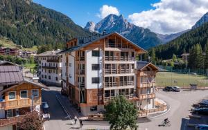 an apartment building with mountains in the background at Locanda degli Artisti Art Hotel in Canazei