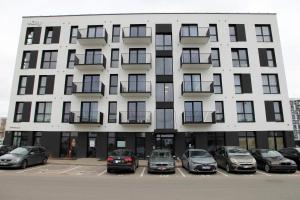 een wit gebouw met auto's geparkeerd op een parkeerplaats bij Warmzy Home - Modern 2 Rooms Apartment With Free Parking in Vilnius
