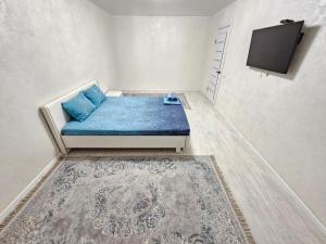 um pequeno quarto com um sofá e uma televisão em Sapar APARTMENTS 24 em Aqtöbe