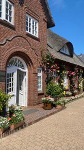 ein Backsteingebäude mit einer weißen Tür und Blumen in der Unterkunft Hotel und Restaurant Jörg Müller in Westerland