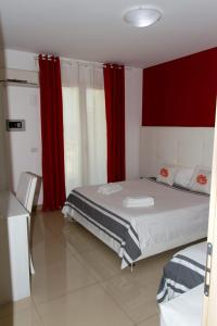 1 dormitorio con 1 cama grande y cortinas rojas en Riviera Ionica, en Santa Teresa di Riva