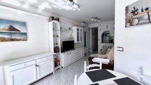 a white living room with a table and a television at Alba Apartman Torrevieja in Torrevieja