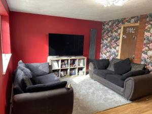 uma sala de estar com 2 sofás e uma televisão de ecrã plano em Barwell Manor - WFH Suite em Leicester