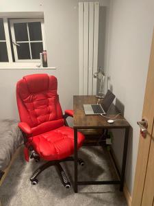 einem roten Stuhl neben einem Schreibtisch mit einem Laptop in der Unterkunft Barwell Manor - WFH Suite in Leicester