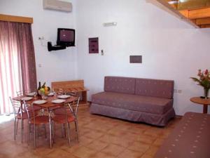 a living room with a couch and a table and chairs at LAKIS APPARTMENTS in Faliraki