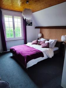 a bedroom with a large bed with a purple blanket at Chambre spacieuse privée avec Jaccuzi in Talmas