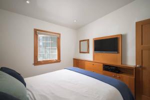 a bedroom with a bed and a flat screen tv at Cottage C on Ocean View in Pismo Beach