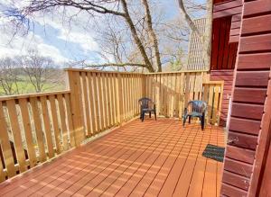 deux chaises assises sur une terrasse avec une clôture dans l'établissement Peaceful Cowslip Lodge - Finlake Spa Resort in Devon, à Chudleigh 35 autres photos