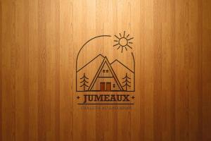 un logotipo en un fondo de madera con una casa en Chalet Jumeaux Mont Édouard Ski & Nature en LʼAnse-Saint-Jean