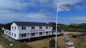 a white building with a flag in front of it at Klithjem Badehotel in Vejers Strand