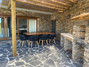 a stone walled patio with a wooden table and chairs at Casa da Meia Encosta in Arganil