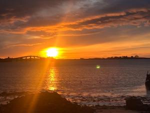 um pôr-do-sol sobre a água com uma ponte ao fundo em Ytterland Apartments em Ålesund