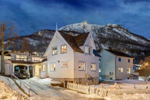 a house in the snow with a mountain in the background at Villa Arctica in Tromsø