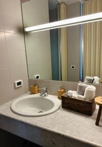 un lavabo con espejo y una cesta de toallas. en Eporedia 222 en Ivrea
