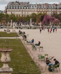 Expo Paris Versailles في باريس: أناس جالسون على كراسي في حديقة أمام مبنى