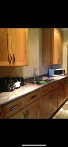 a kitchen with wooden cabinets and a sink and a microwave at Heart West Haven in Priddis