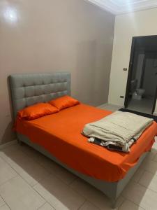 a bed with orange sheets and orange pillows in a bedroom at THURIN IMO (Vauvert) in Saint-Louis