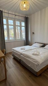 a large bed in a room with windows and a chandelier at CityCenterApartments/M32/6 in Bielsko-Biała